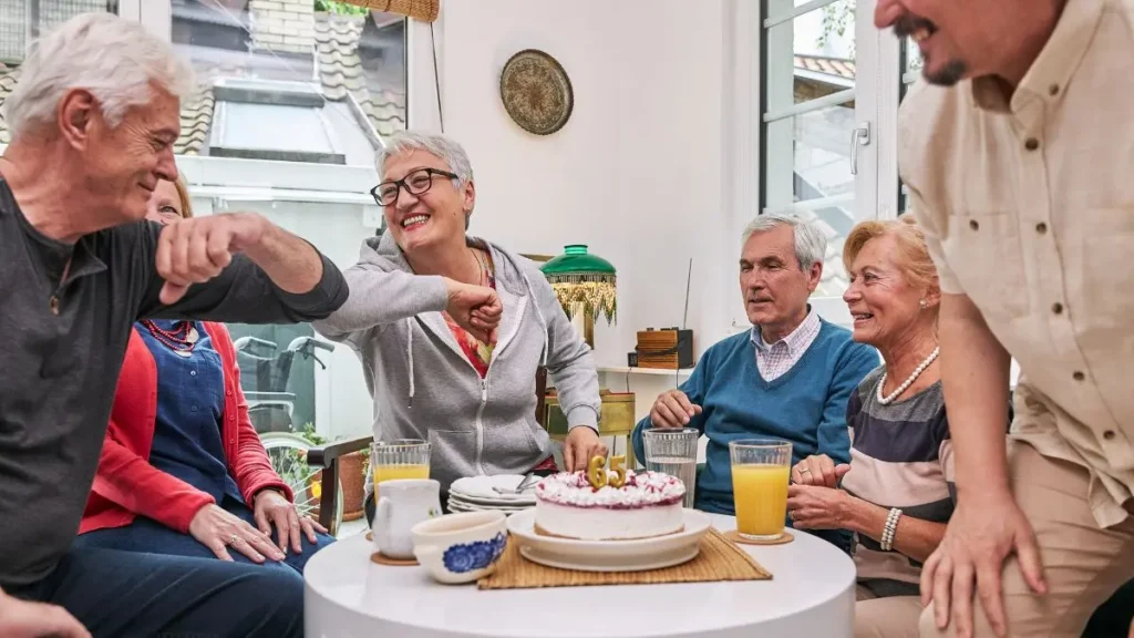 senior-community-celebration-group-laughing-around-birthday-cake