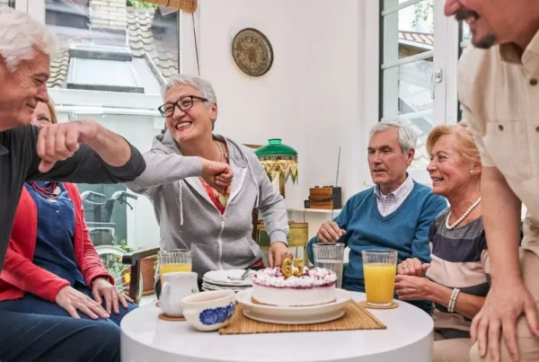 senior-community-celebration-group-laughing-around-birthday-cake