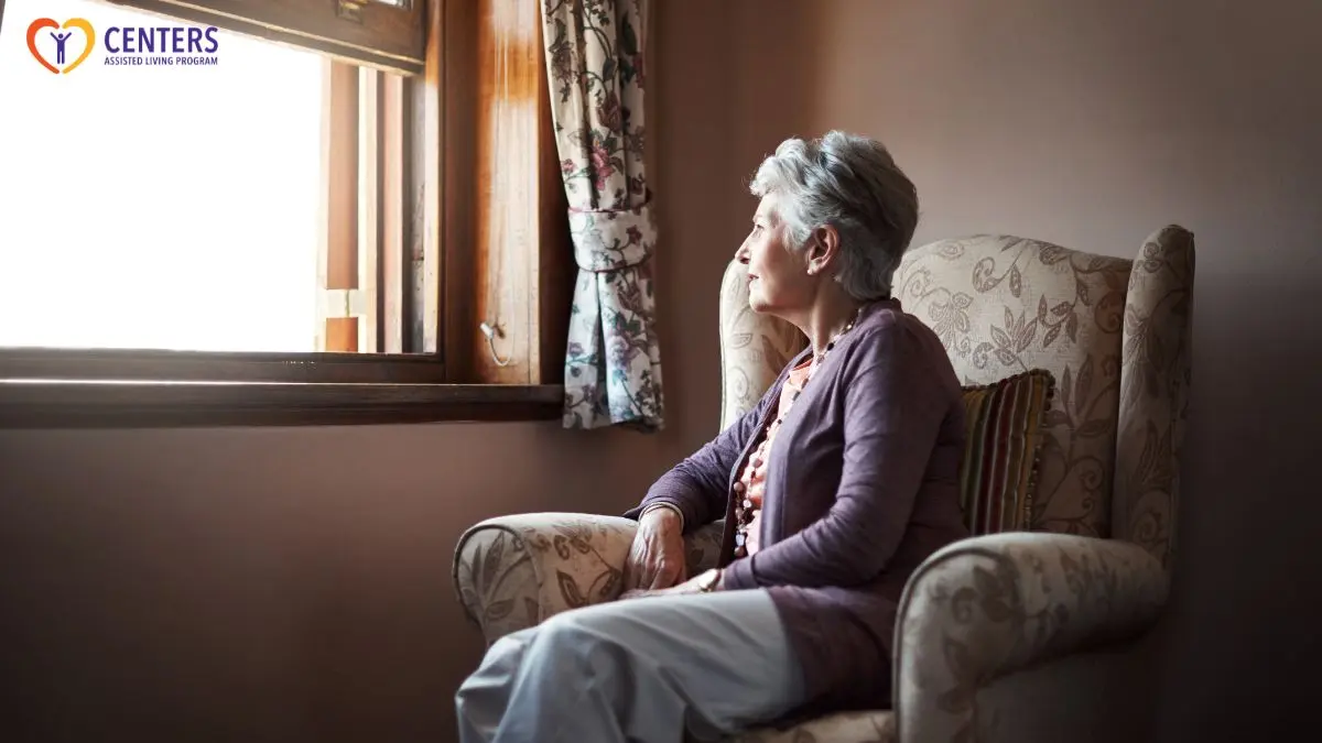 senior-woman-sitting-by-window-looking-out-thoughtful-at-home